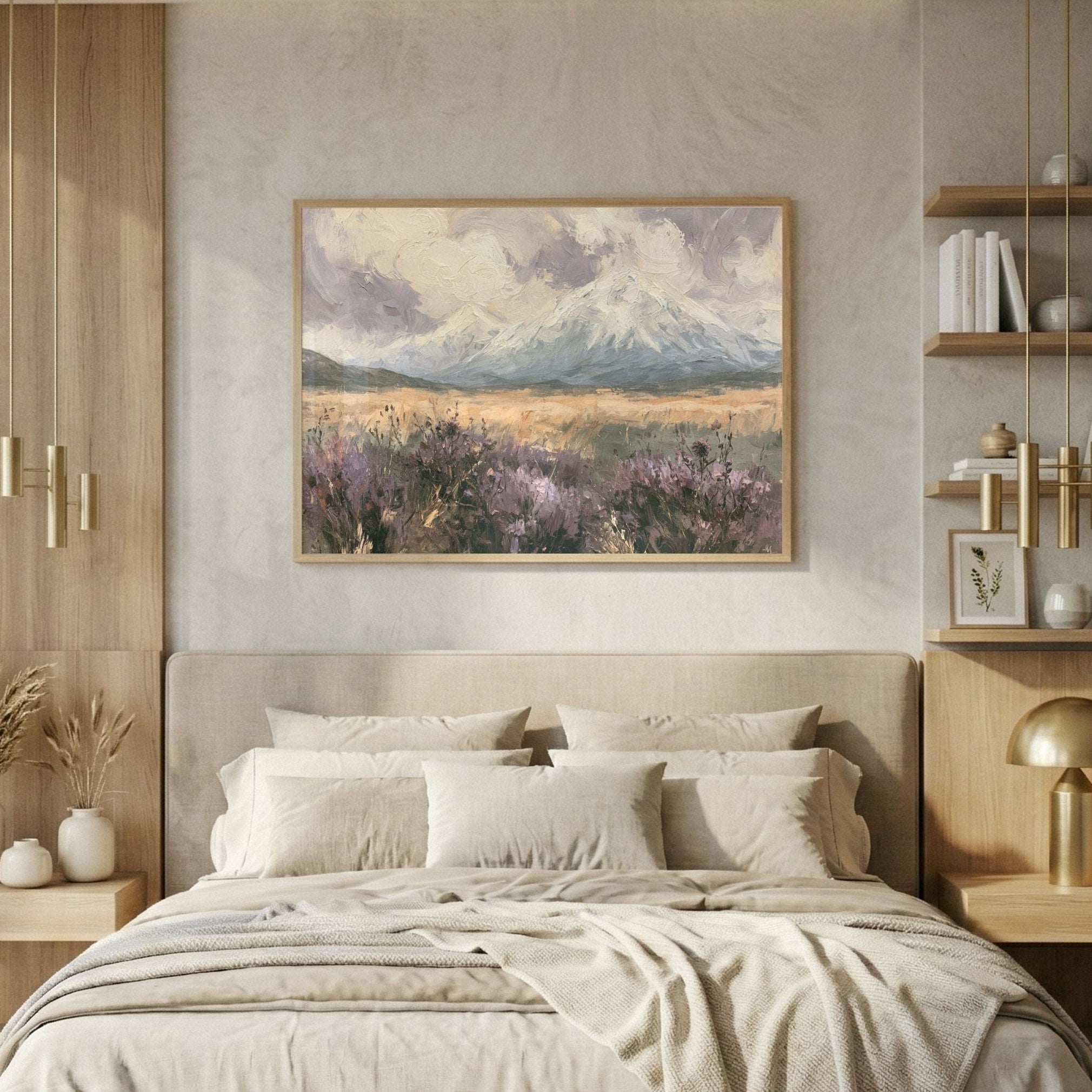 A beautifully styled modern bedroom featuring a large framed landscape painting of purple lavender fields and snow-capped mountains on the wall above a neatly made bed with beige linens. The room is decorated with light wood shelving, pendant lights, and a large window on the left.